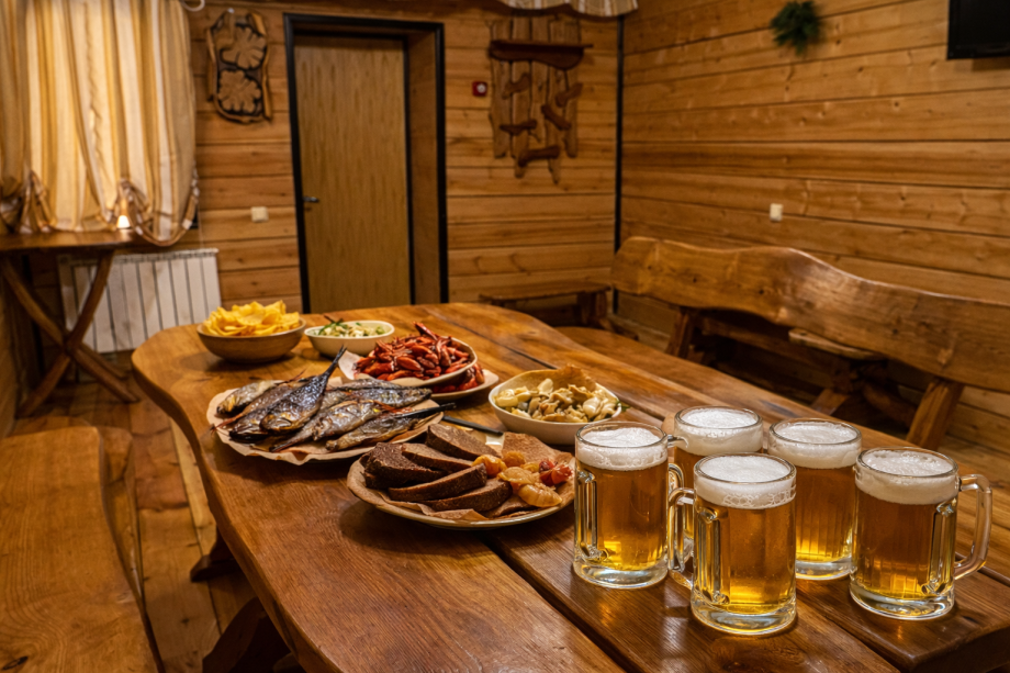 Комната отдыха русской бани с деревянным столом, пивом и закусками на базе отдыха "Аркадия"