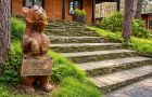 Входная зона бани с деревянной скульптурой на территории базы отдыха