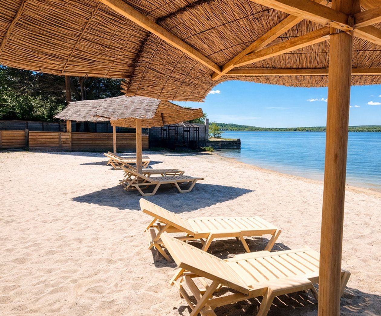 Пляжная зона с лежаками на берегу водоёма летом