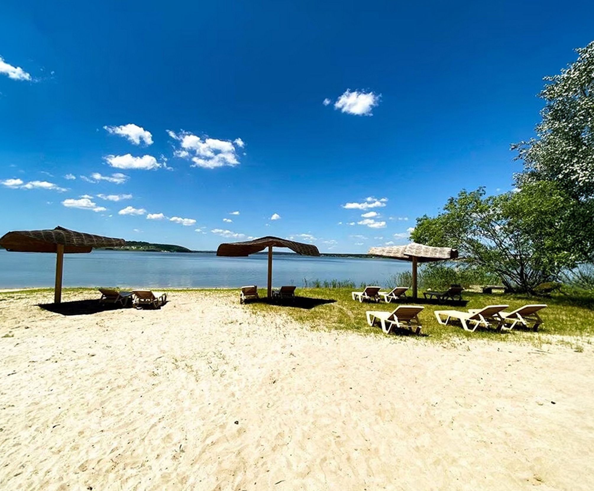 Летний пляж и вид на водоём на территории базы отдыха